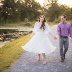 An engaged couple taking romantic engagement photos near a scenic pond in Maryland during a breathtaking sunset.