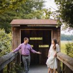 An engaged couple standing on a wooden bridge, capturing their romantic Maryland engagement photos as the mesmerizing sunset adds a touch of magic to the scene.