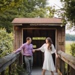 An engaged couple standing on a wooden bridge in the woods during a sunset in Maryland.