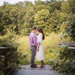 An engaged couple sharing a romantic kiss on a bridge during sunset for their Maryland engagement photos.