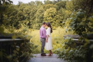 An engaged couple sharing a romantic kiss on a bridge during sunset for their Maryland engagement photos.