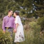 An engaged couple standing in tall grass during sunset in Maryland, capturing beautiful engagement photos.