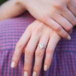 A breathtaking engagement ring glimmers on a woman's hand as the mesmerizing Maryland sunset bathes their love in warm hues.