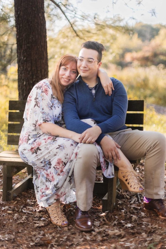 An engagement couple posing on a bench in the woods at Patuxent Research Refuge.