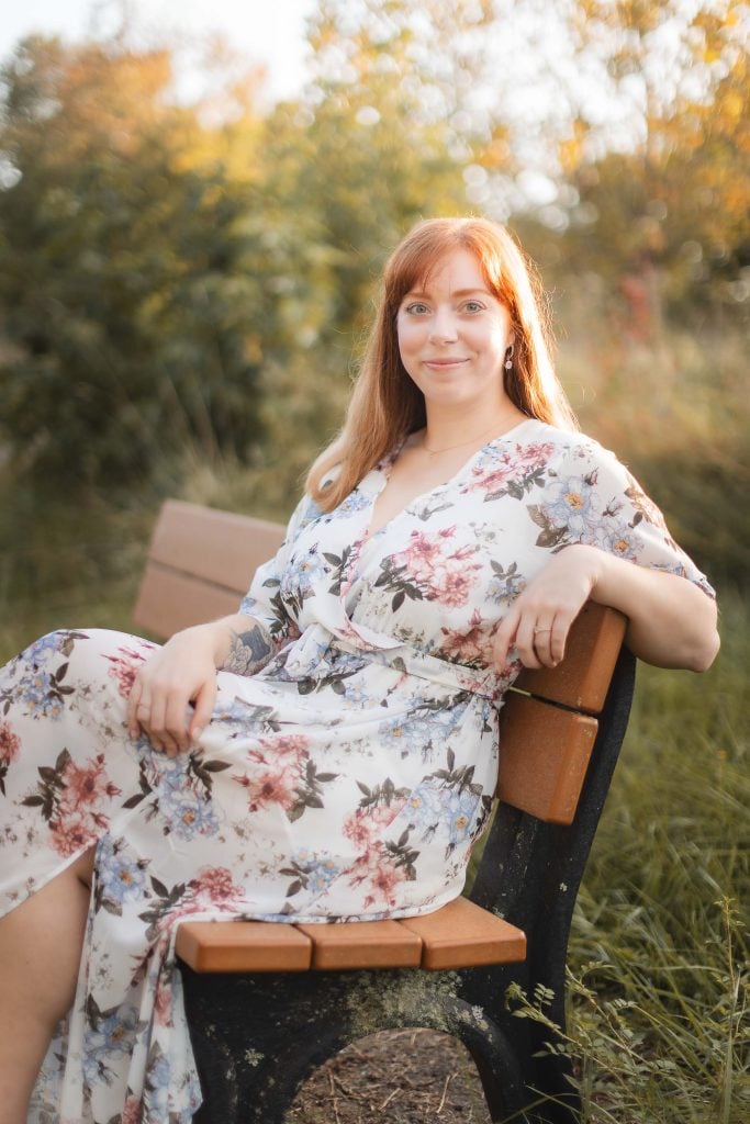 A woman in a floral dress sitting on a wooden bench at Patuxent Research Refuge.