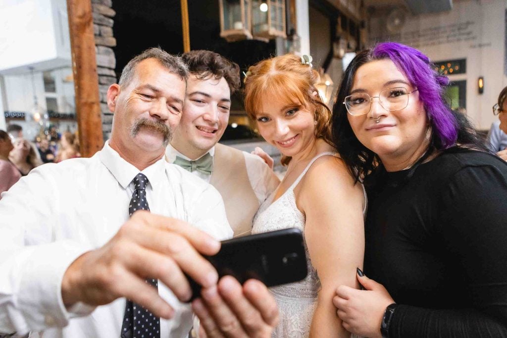 Wedding reception guests taking a selfie with a cell phone at Blackwall Barn & Lodge.