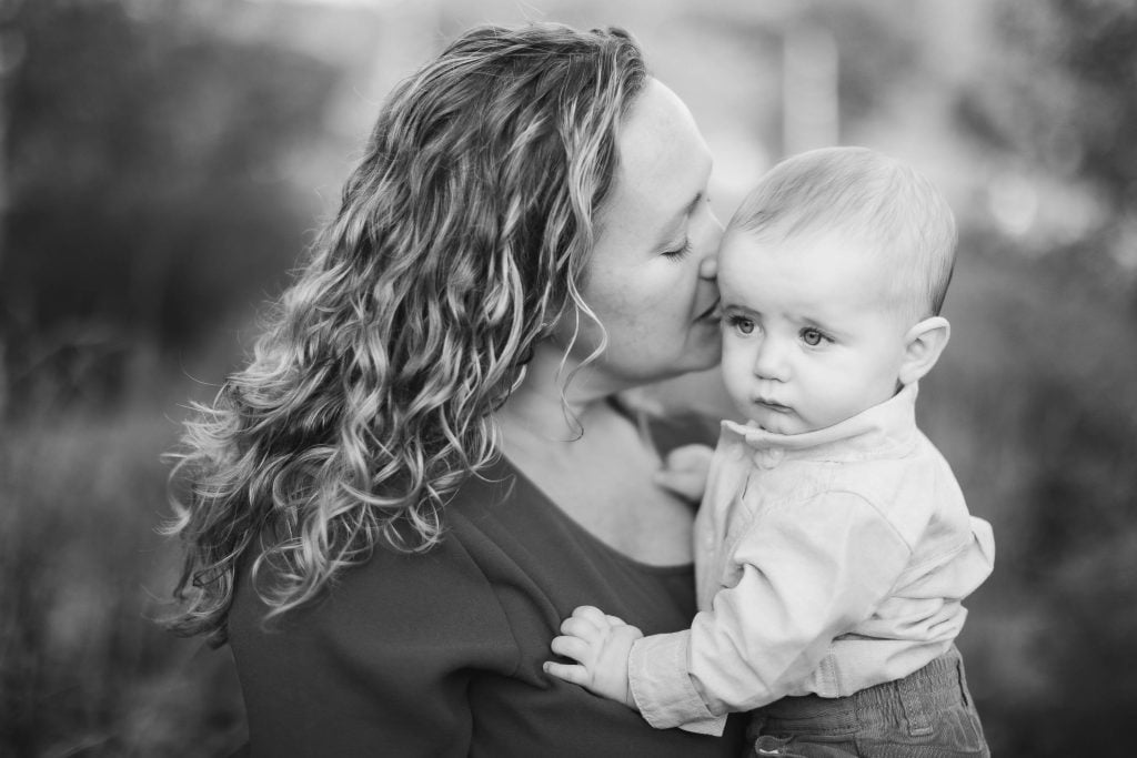 A black and white photo of a woman kissing her baby at Quiet Waters Park, Annapolis Maryland.