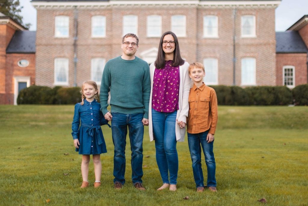 A family stands in front of Belair Mansion, a large brick house in Bowie Maryland.