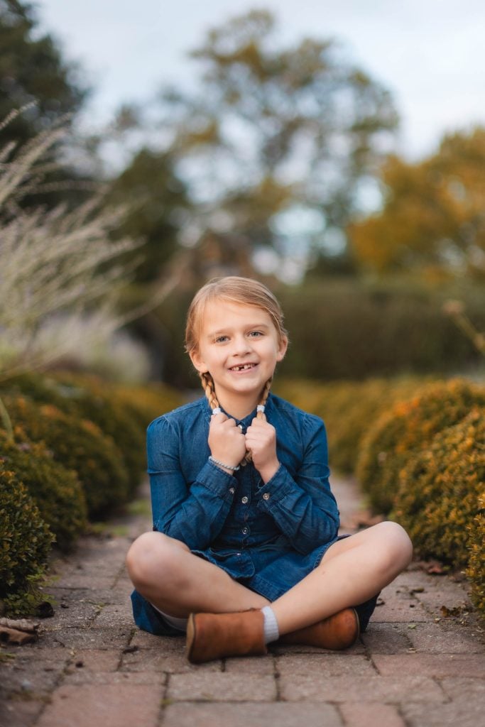 A little girl sitting on a brick path in a garden at Belair Mansion in Bowie, Maryland.