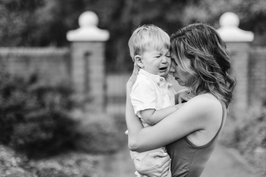 A black and white photo of a woman hugging her son, capturing a heartfelt family moment.