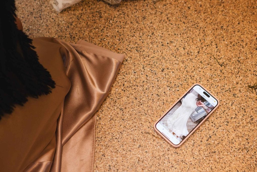 A smartphone displaying an image of a woman in a wedding dress lies on a speckled surface next to draped fabric, evoking memories of the beautiful reception at The Barns at Hamilton Station.